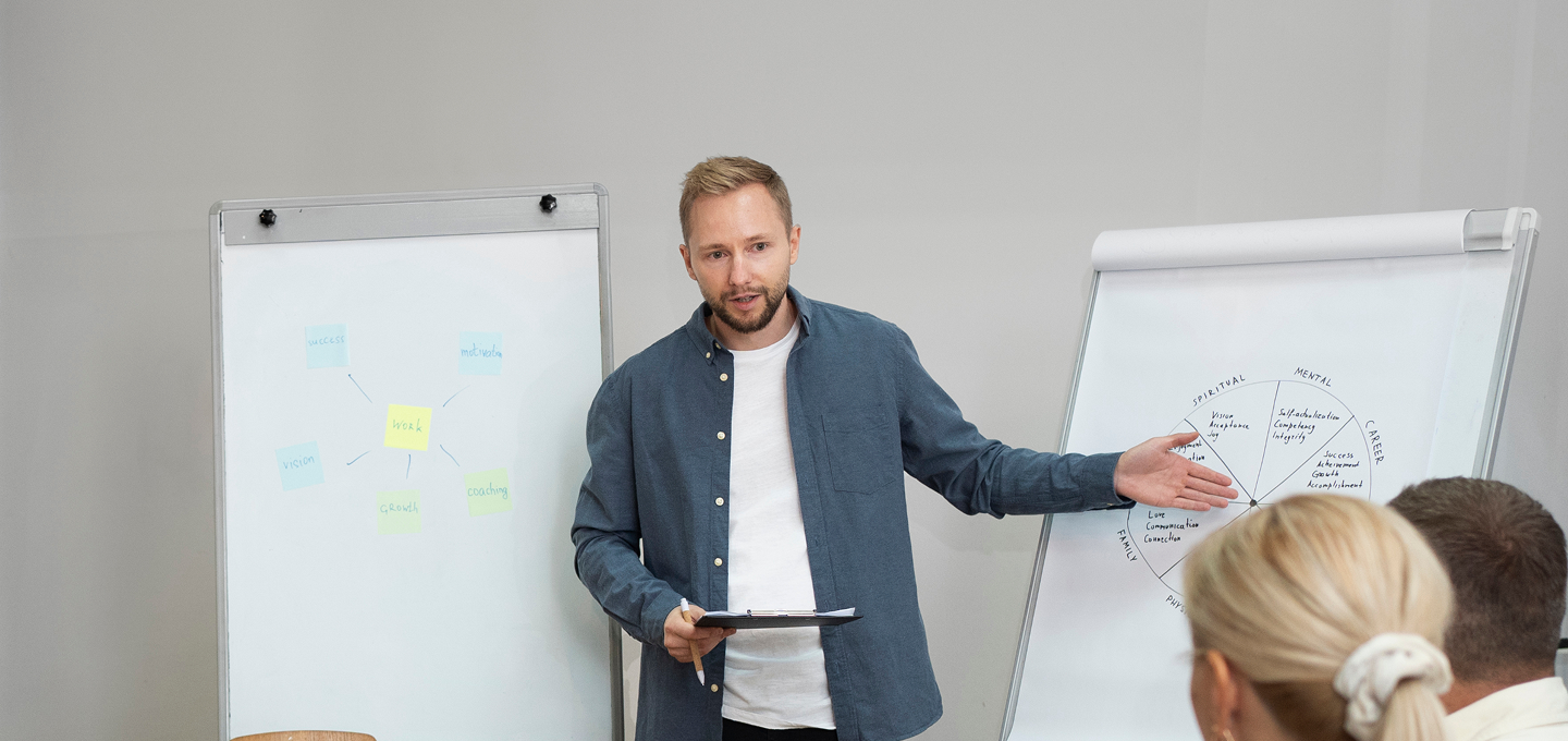 Man in a suit giving a presentation to an audience in a lecture hall.